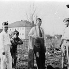 Myron Edward "John" Ames with sons "Phil" and "Bob" and friend in front of their home at 6th Avenue and F Street, ca. 1933.  The Anchorage Public School is shown in the background.
