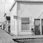 U.S. Commissioner' office, 5th Avenue and E Street, Anchorage, 1916-1917. Leopold David was U.S. Commissioner during his first year in Anchorage, before becoming a lawyer in private practice. Daughter Caroline David stands by the door.