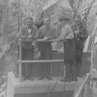 Oscar Gill (third from the left) and several others inspect the hydroelectric dam on the Eklutna River below Eklutna Lake,  ca. 1930.  The hydroelectric project came on-line in 1929, providing cheaper power for Anchorage and the Alaska Railroad yards than the Alaska Railroad’s old coal burning power plant.  To Gill’s left is James Delaney, who preceded Gill as mayor of Anchorage.