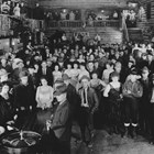 The Whitneys, like many Anchorage residents, were extras for some of the crowd scenes in Austin E. “Cap” Lathrop’s 1923 Alaska movie production “The Chechakos.” This photograph lists Bud Whitney as the man in the center front with an open leather coat, squared off tie, and laced knee boots. Daisy Whitney is listed as the woman in the dark dress standing next to the roulette table on the left side of the image.