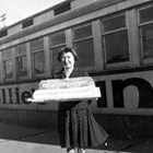 Nellie Brown holding a cake made to resemble her diner, which she operated out of a railroad car in Anchorage during the early 1940s