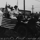 Another view of Joseph "Joe" Spenard driving in a parade, this time touting the American Red Cross, possibly during World War I in 1917 or 1918. Whether he had the first automobile or truck in Anchorage is less certain.